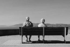 Couple de seniors assis sur un banc devant une vue sur la montagne en noir et blanc